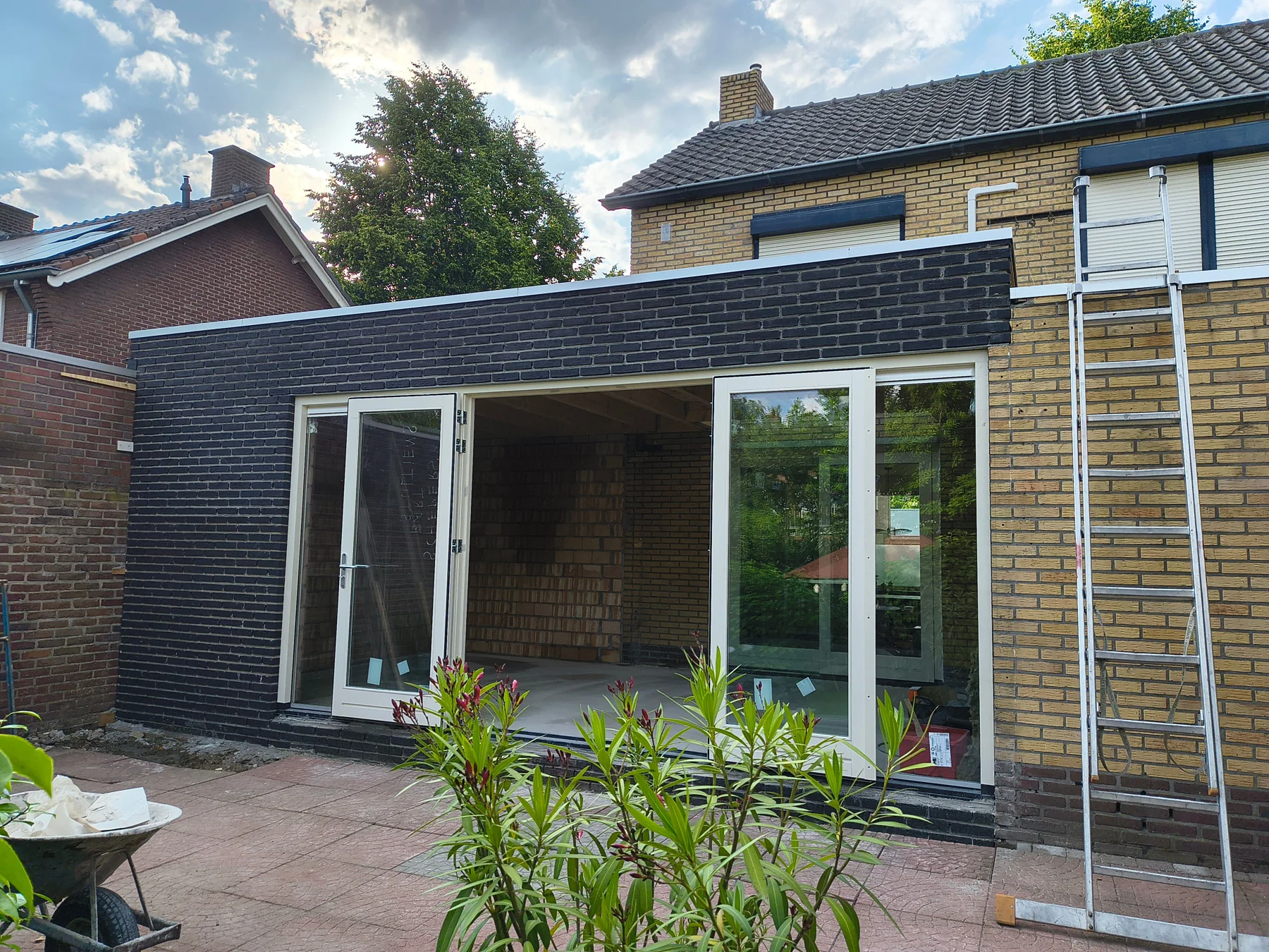 Buitenzijde van een aanbouw met donkere bakstenen en witte deuren
